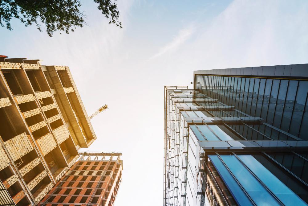 Vue en contre-plongée d’un immeuble en construction et d’un bâtiment moderne en verre
