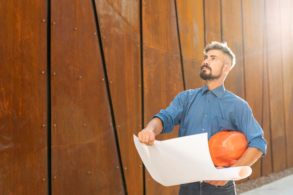Auto entrepreneur dans le bâtiment, casque et plan à la main