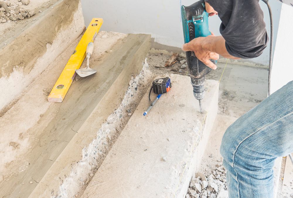 Travaux de rénovation d’un escalier en béton avec perforateur et outils de maçonnerie